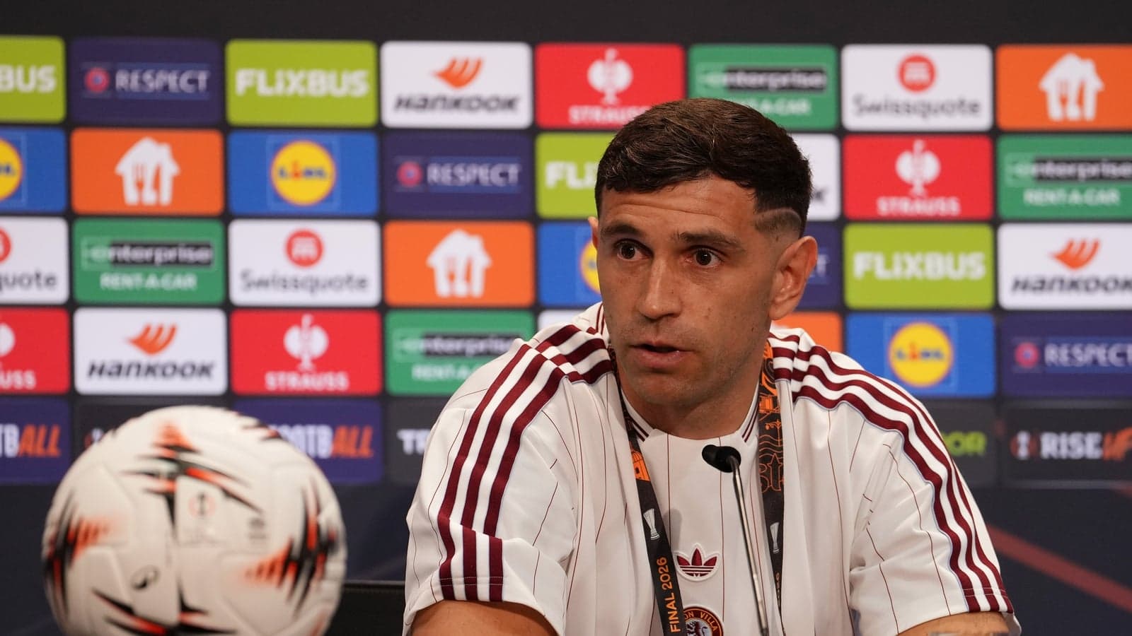 Jugador en conferencia de prensa con balón de fútbol