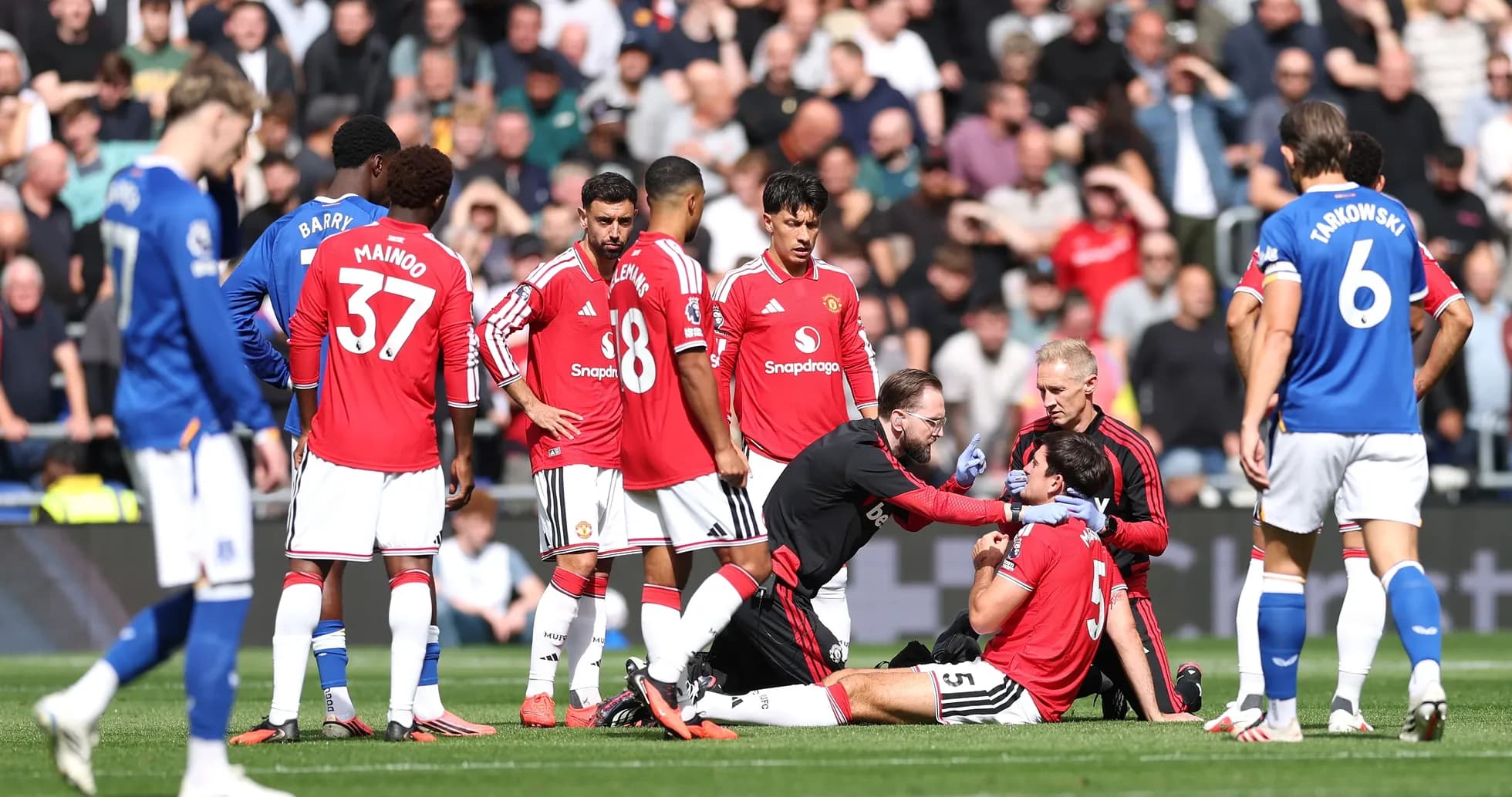 Jugadores de Manchester United rodeando a un compañero herido