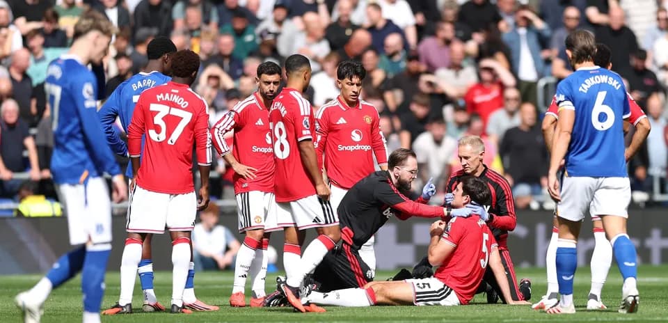 Jugadores de Manchester United rodeando a un compañero herido