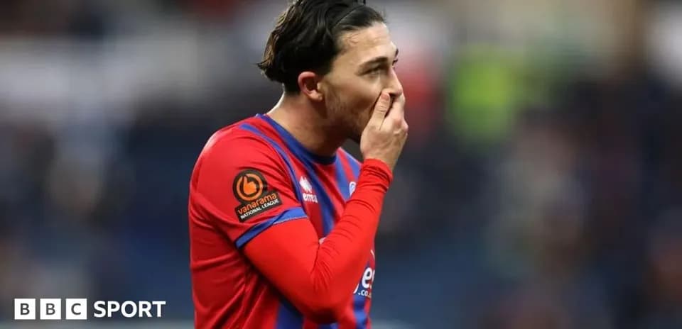 Jugador con camiseta roja y azul tocándose la cara