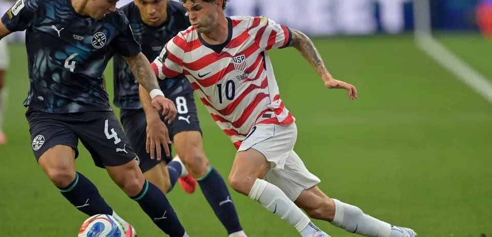 Christian Pulisic dribbling past two defenders