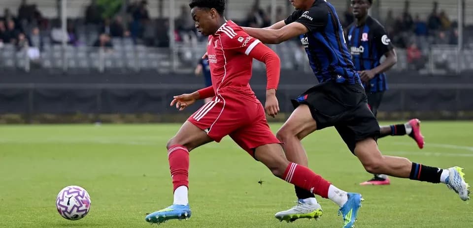 Jugador de Liverpool corriendo con balón, rival persiguiéndolo