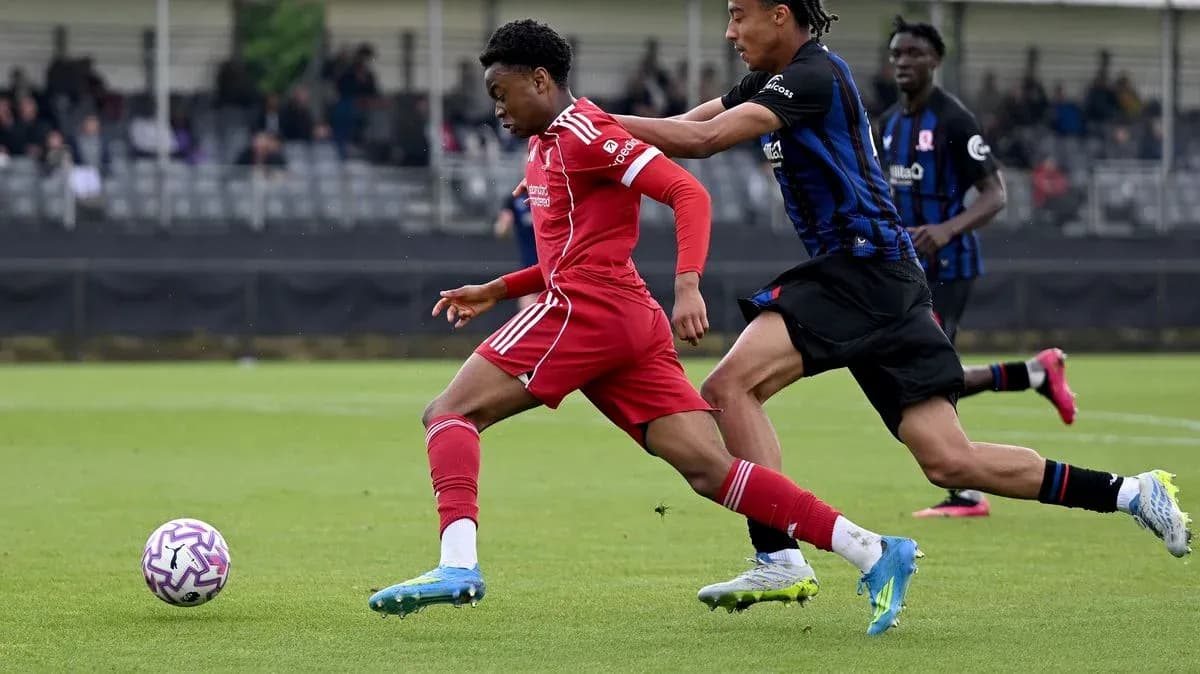 Jugador de Liverpool corriendo con balón, rival persiguiéndolo
