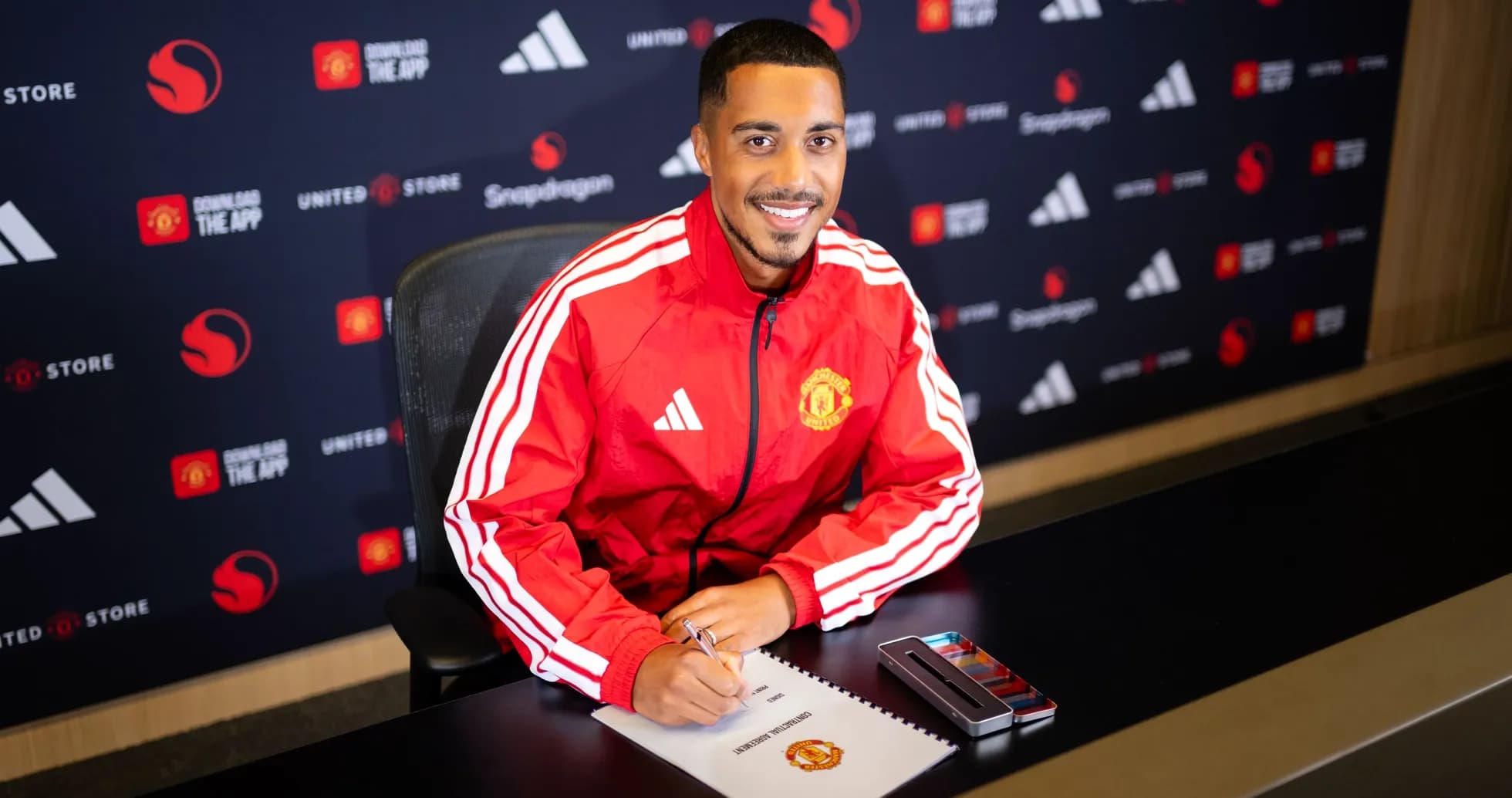 Jugador firmando contrato en mesa de presentación