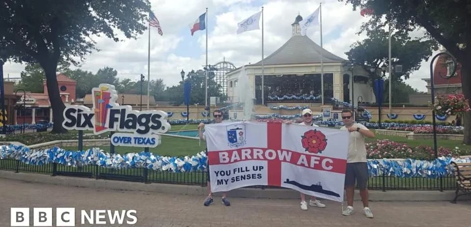 Dos aficionados sosteniendo una bandera de Barrow AFC