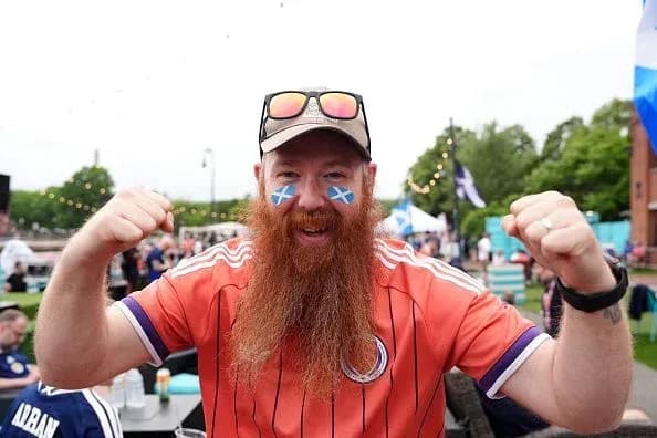 Hincha con camiseta escocesa y barba larga celebrando