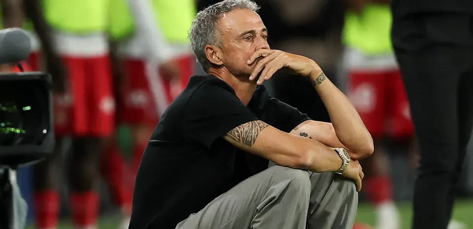 Entrenador sentado durante el partido, pensativo