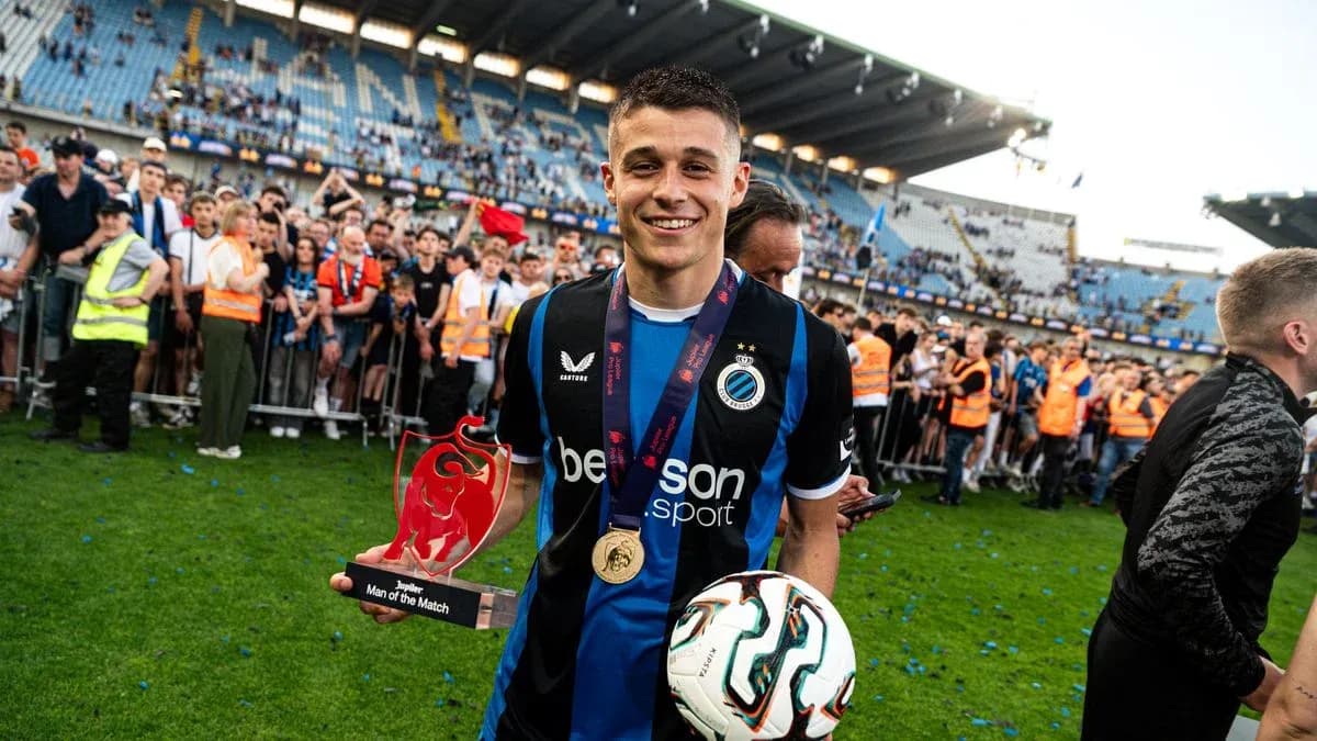 Jugador sosteniendo trofeo y balón en el campo