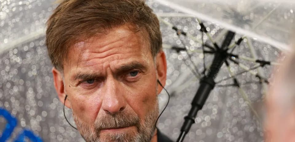 Entrenador bajo paraguas durante la conferencia de prensa