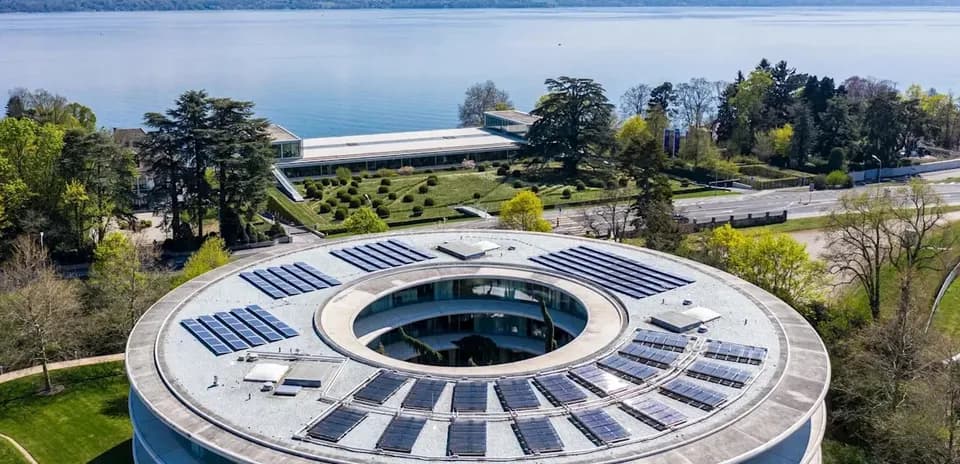 Edificio moderno con paneles solares y lago de fondo