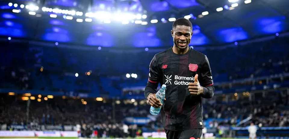 Jugador sonriente sosteniendo botella de agua en campo