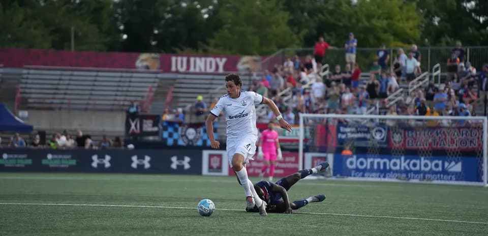 Jugador de Indy Eleven driblando a oponente caído