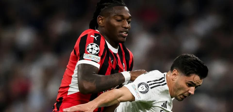 Jugador con camiseta roja sujetando a rival con camiseta blanca