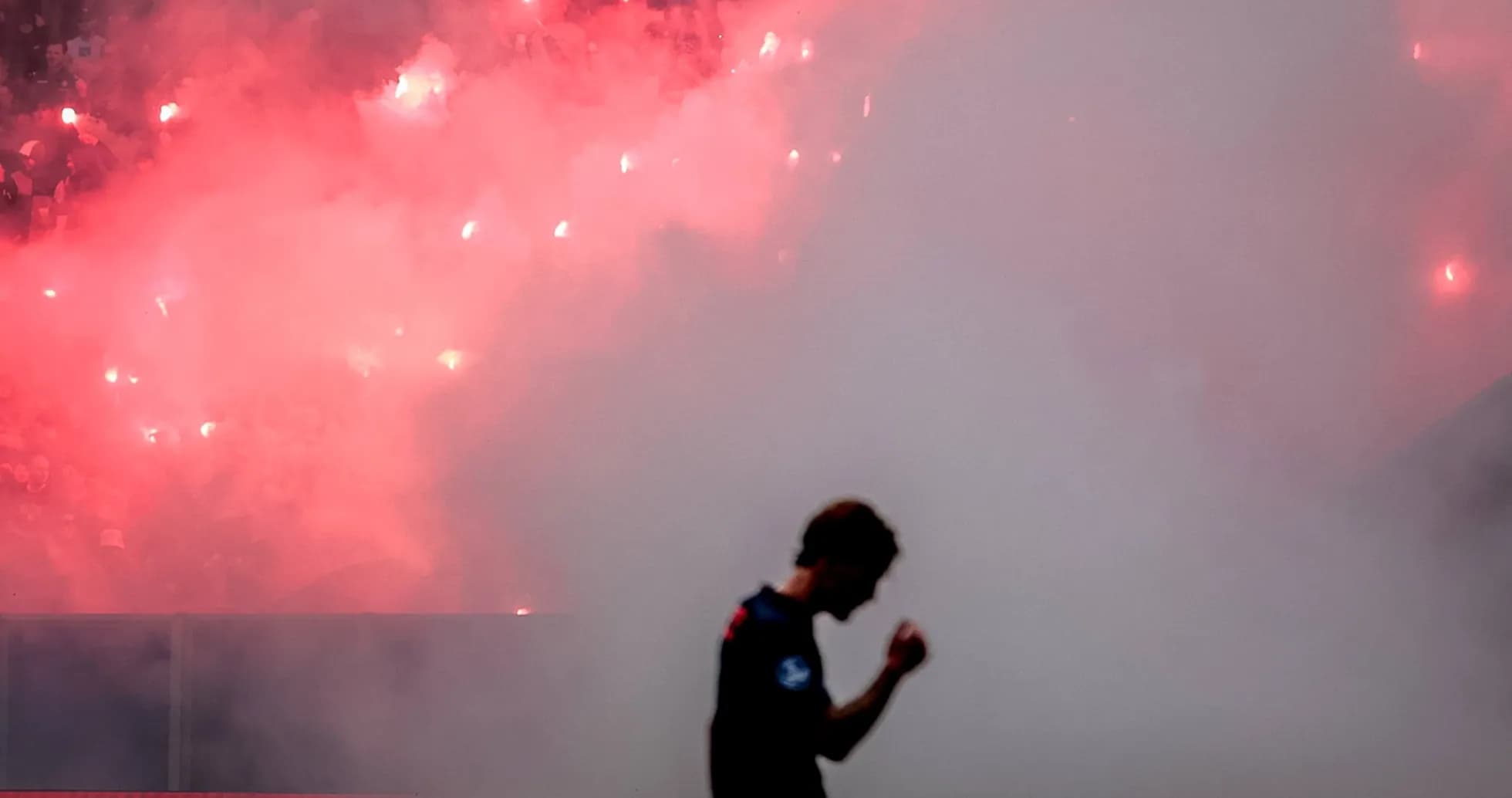 Jugador caminando con humo y bengalas de fondo