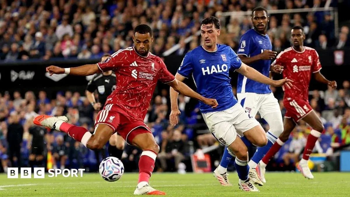 Jugador de Liverpool disparando ante defensa rival