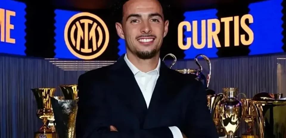 Persona sonriendo frente a trofeos de fútbol