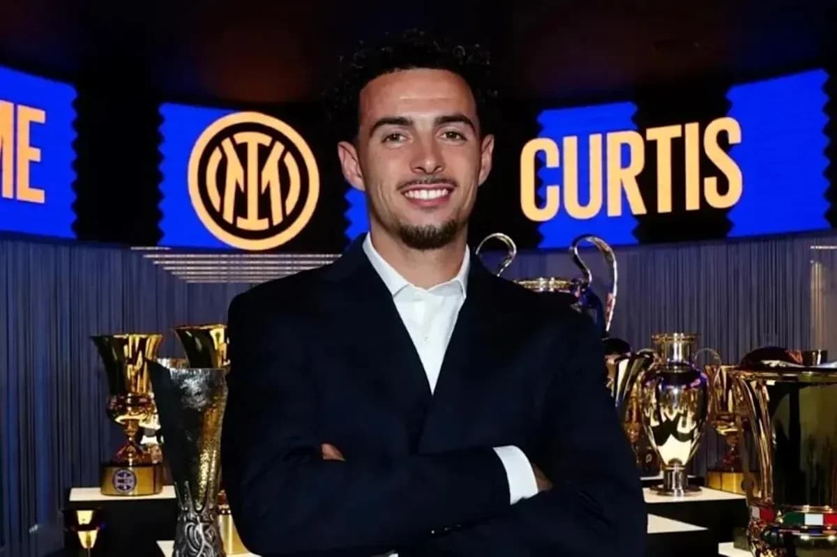 Persona sonriendo frente a trofeos de fútbol