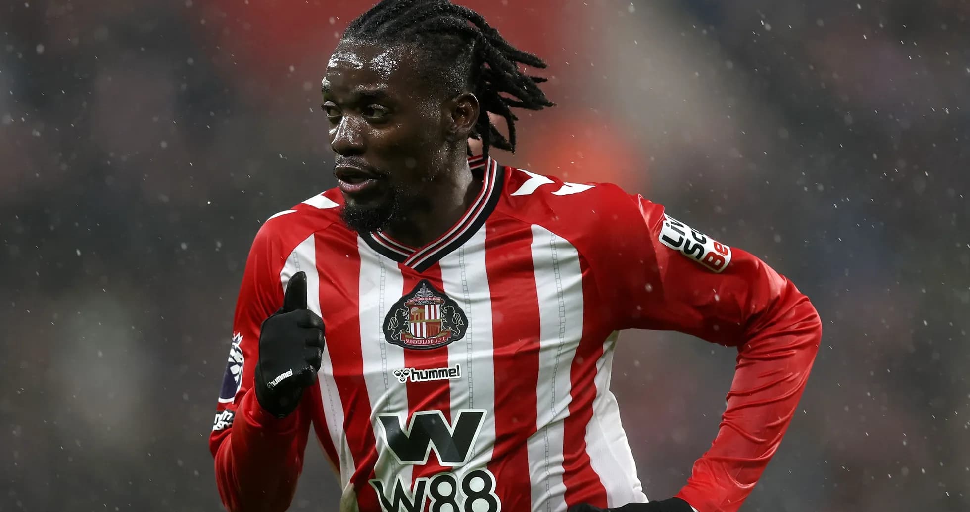 Jugador de Sunderland corriendo en campo lluvioso