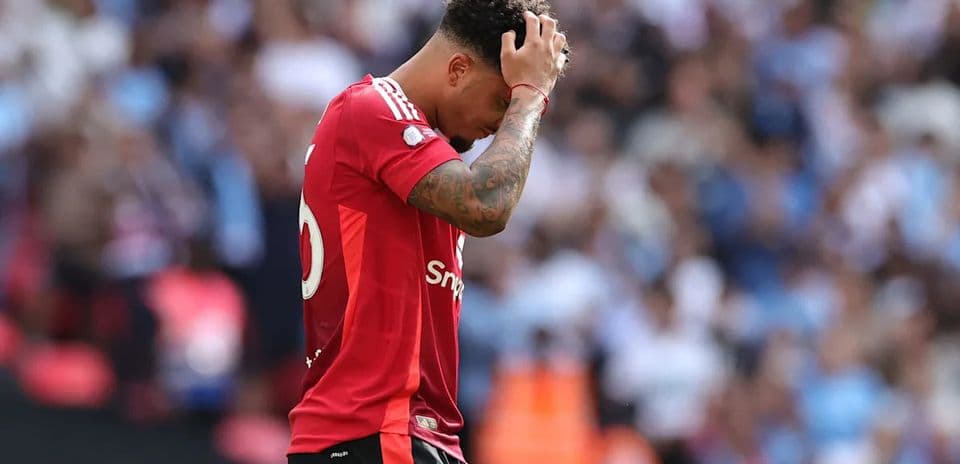 Jugador con camiseta roja cabizbajo en el campo