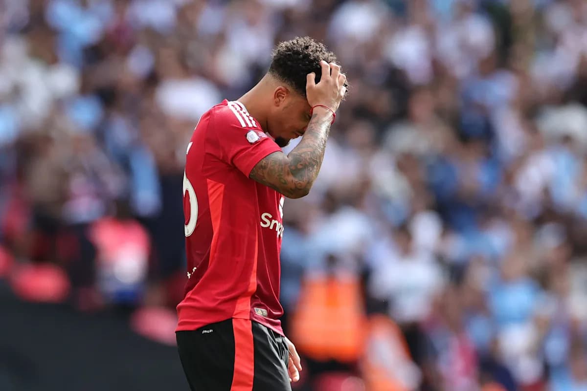 Jugador con camiseta roja cabizbajo en el campo