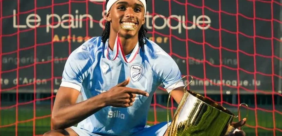 Jugador posando con trofeo en campo de fútbol