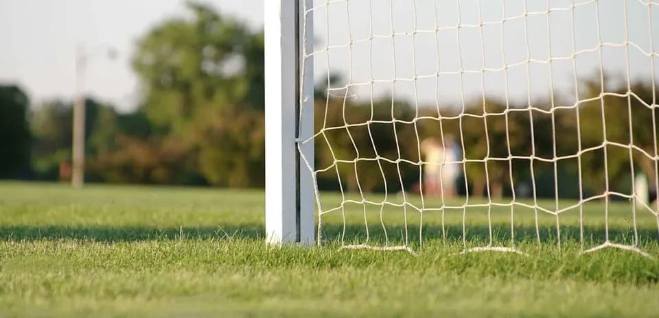 Red de gol en campo de fútbol al atardecer