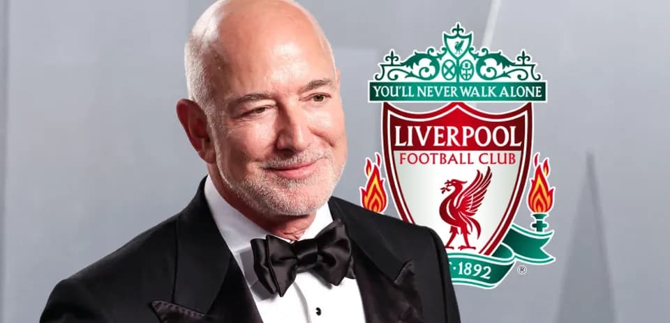 Hombre en traje con logo de Liverpool detrás