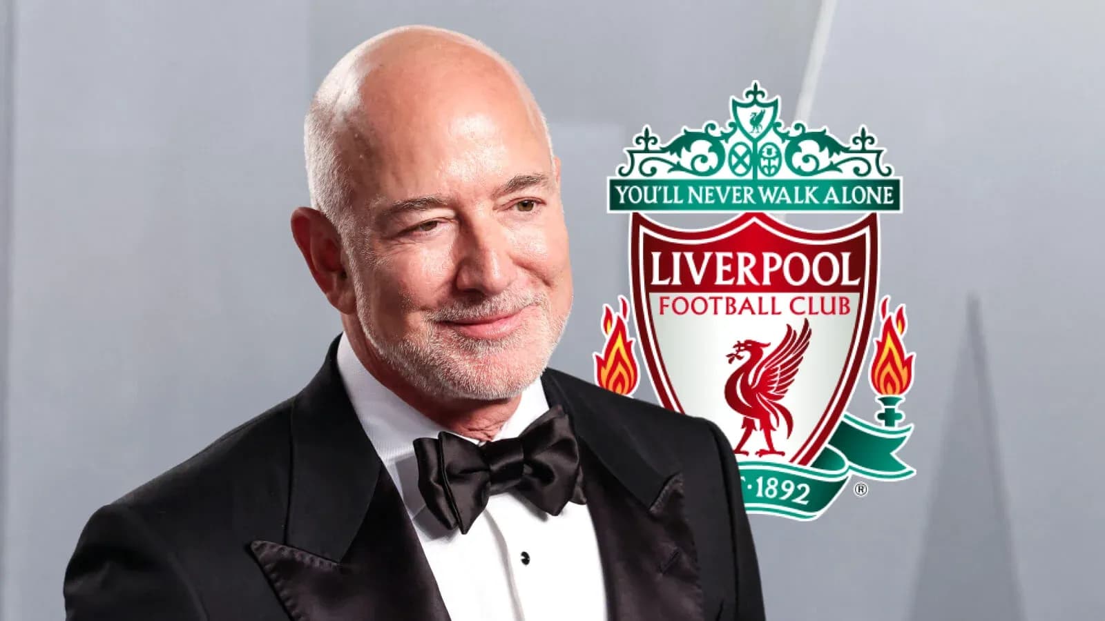 Hombre en traje con logo de Liverpool detrás