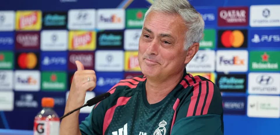 Entrenador en conferencia de prensa con logo de Champions