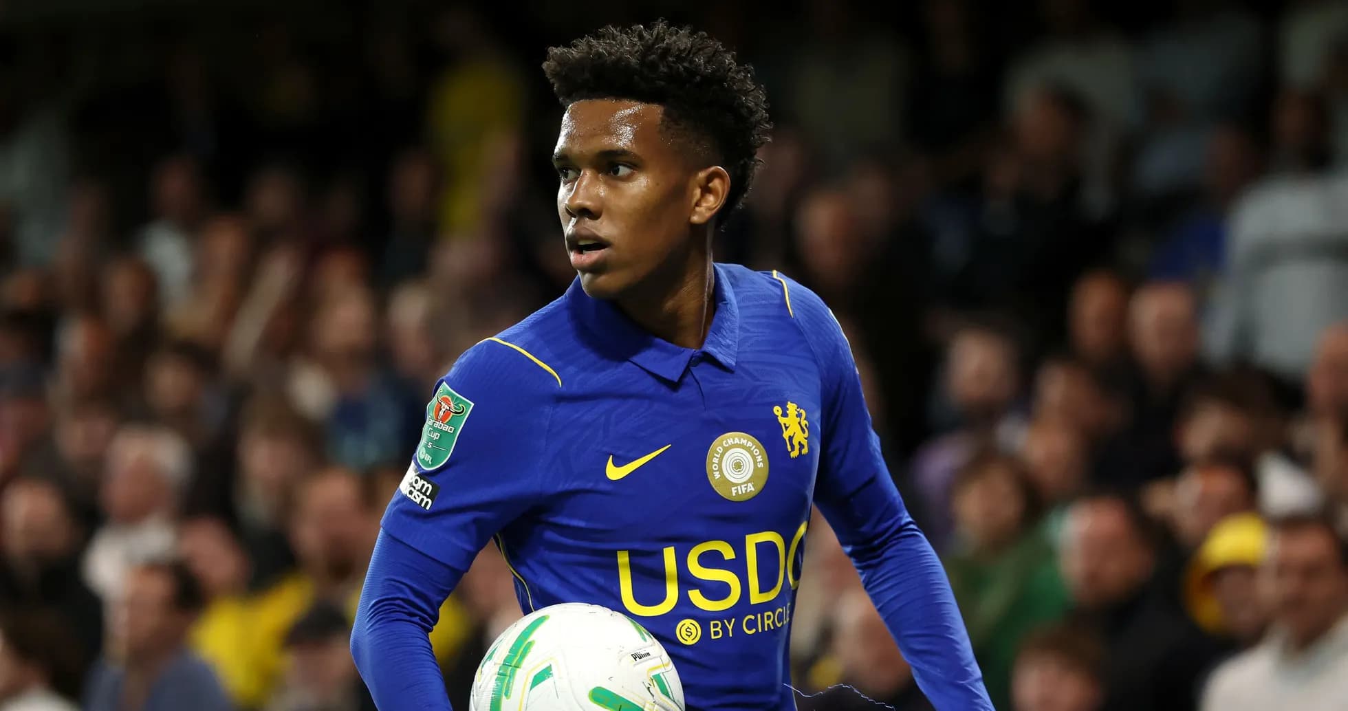 Jugador de Chelsea sosteniendo un balón en el campo