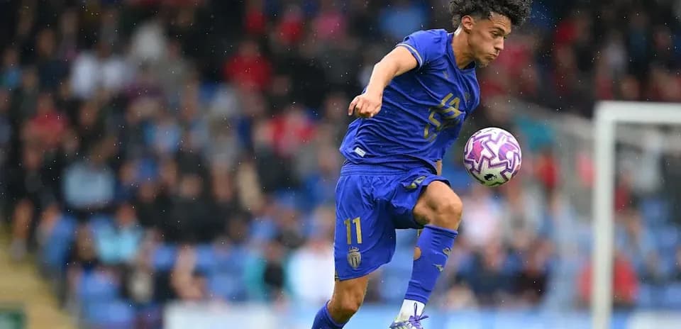Jugador de fútbol controlando balón en campo lluvioso