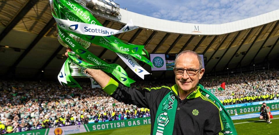 Hombre sosteniendo trofeo con cintas verdes en estadio