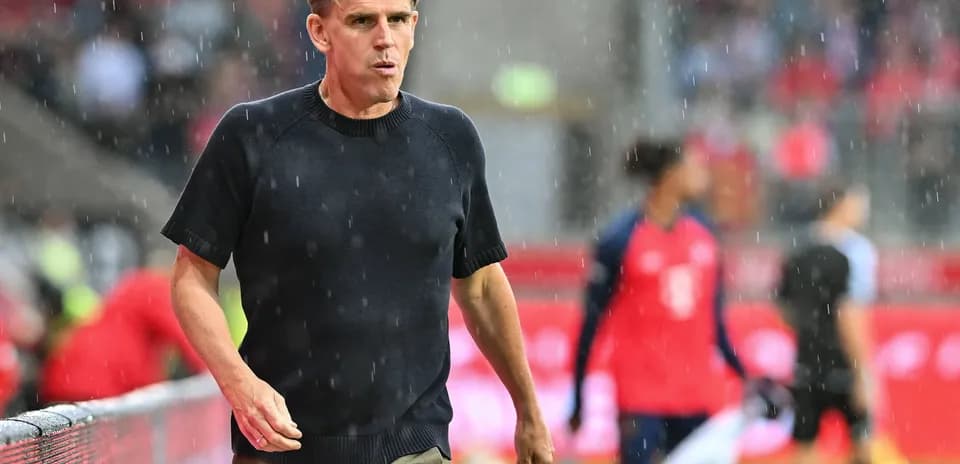 Entrenador caminando bajo la lluvia durante el partido