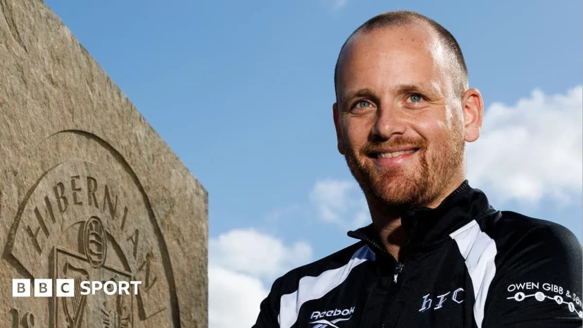 Entrenador posando junto a una piedra con logo