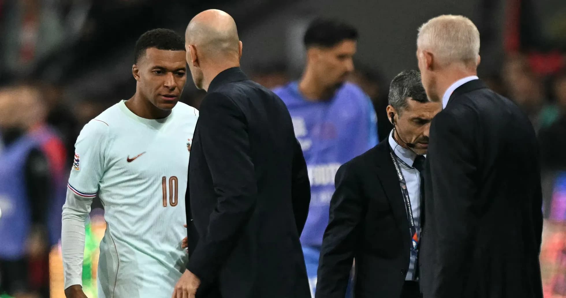 Kylian Mbappé conversando con entrenadores en el campo