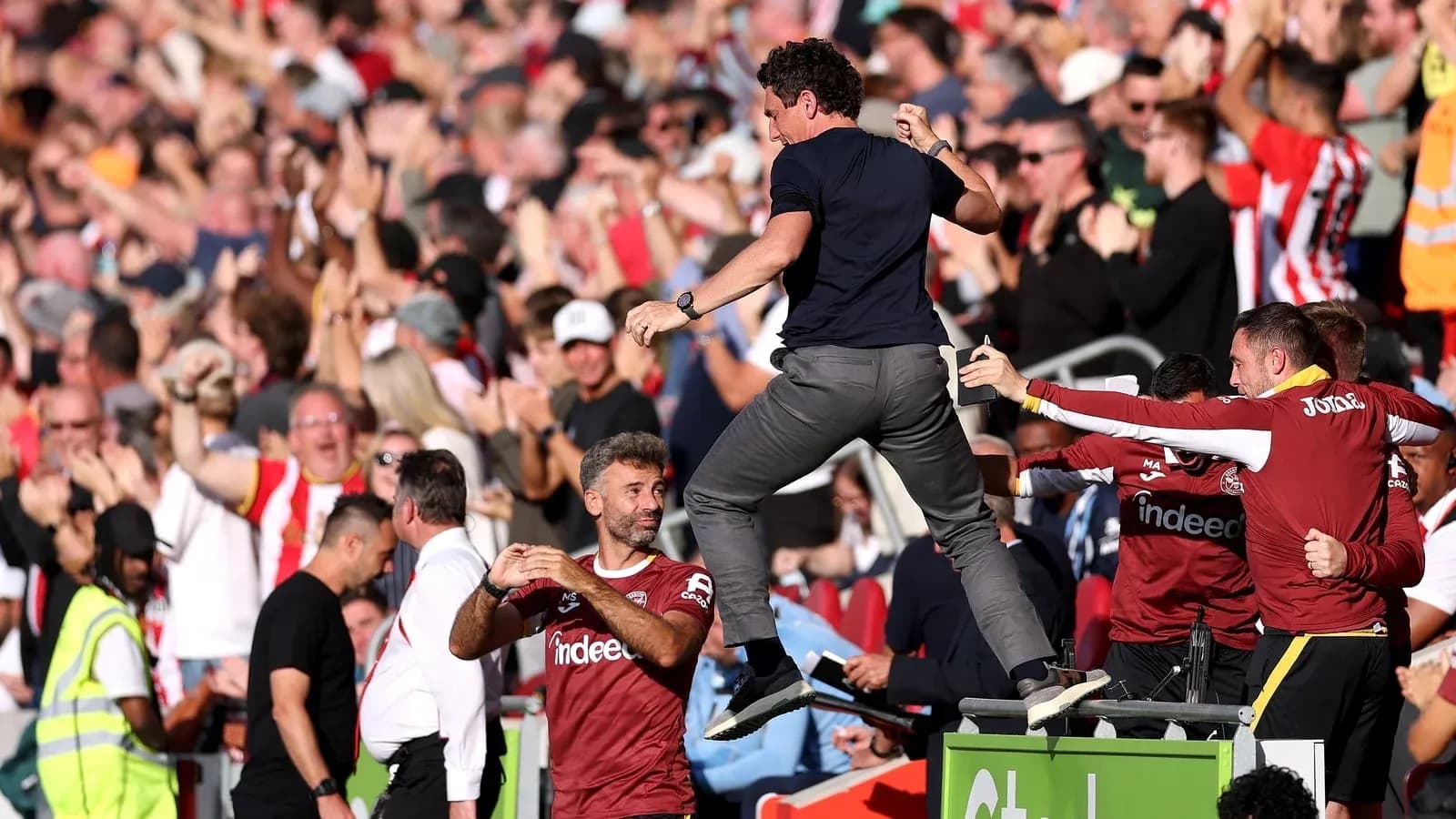 Entrenador celebrando con aficionados durante el partido