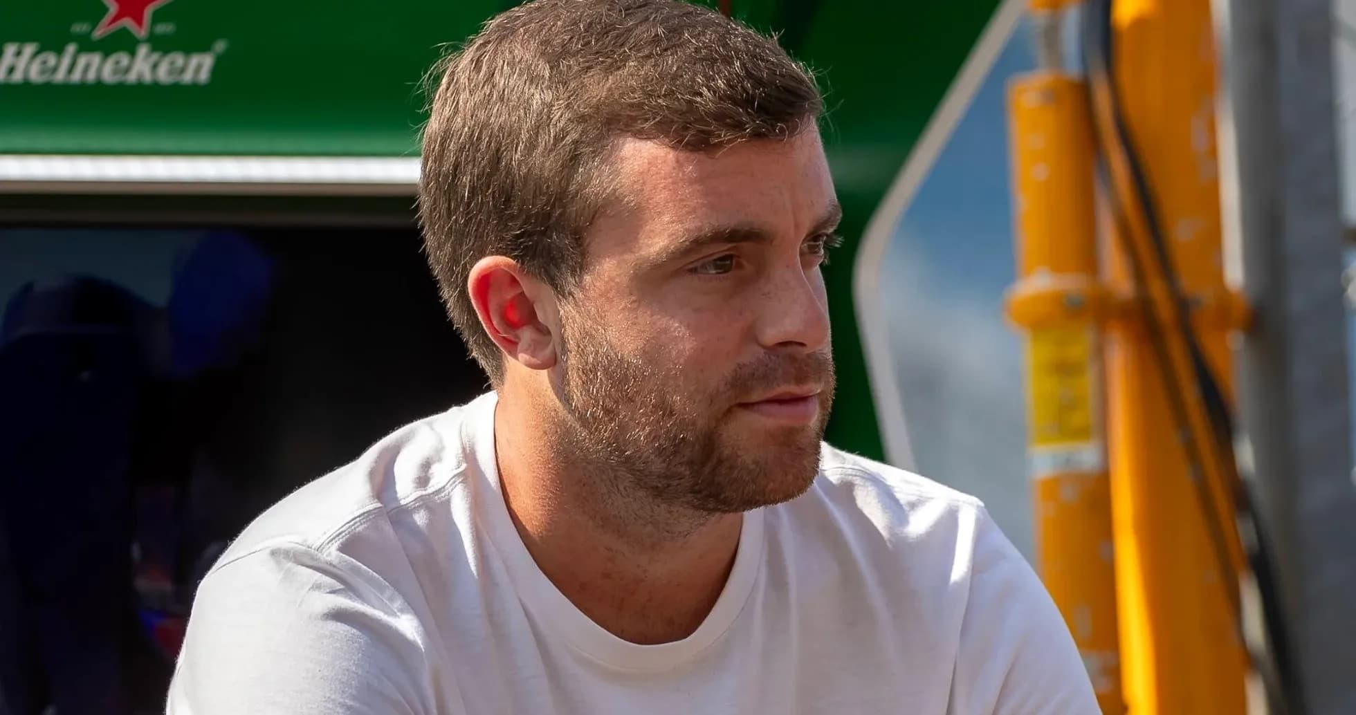 Hombre sentado con camiseta blanca en evento deportivo