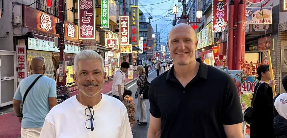 Dos hombres sonriendo en una calle iluminada