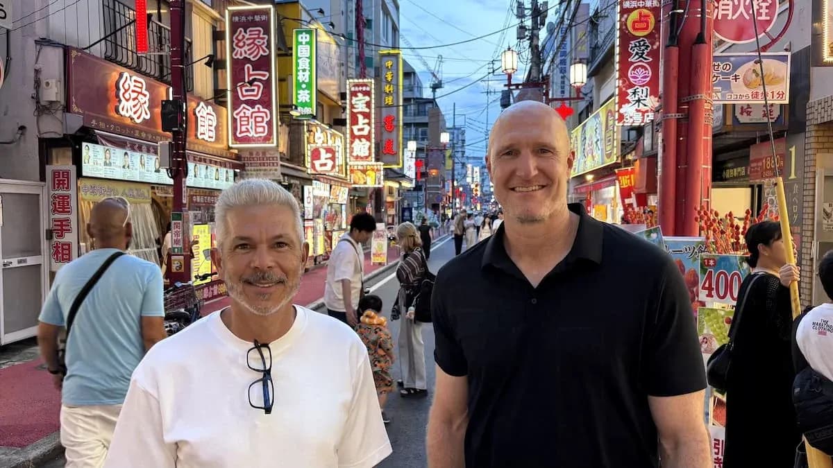 Dos hombres sonriendo en una calle iluminada