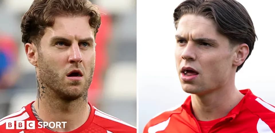 Dos jugadores en uniformes de entrenamiento, uno hablando