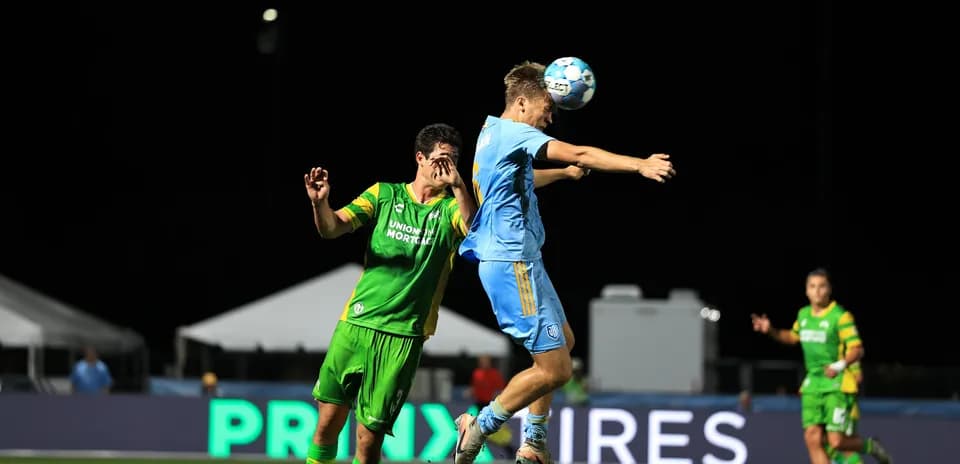 Jugador de Sporting JAX saltando para cabezear el balón