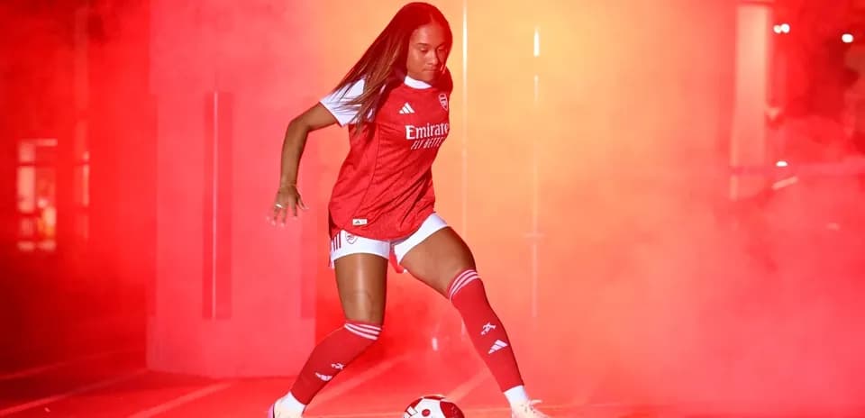 Jugadora de fútbol con balón en ambiente de humo rojo
