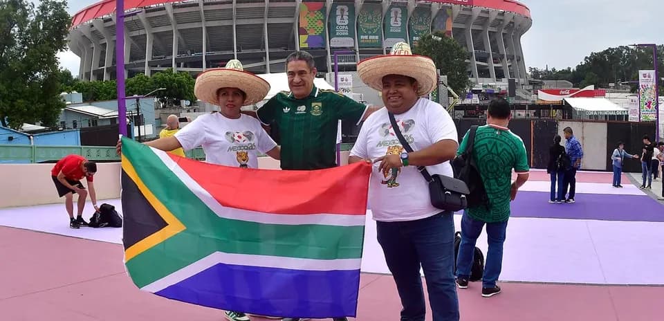Tres aficionados con sombreros sosteniendo bandera de Sudáfrica
