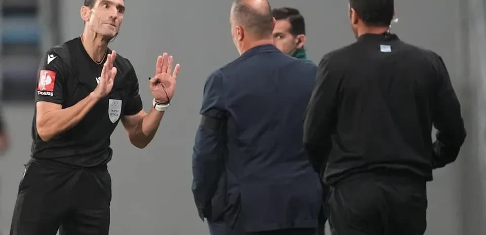 Árbitro conversando con entrenadores durante el partido
