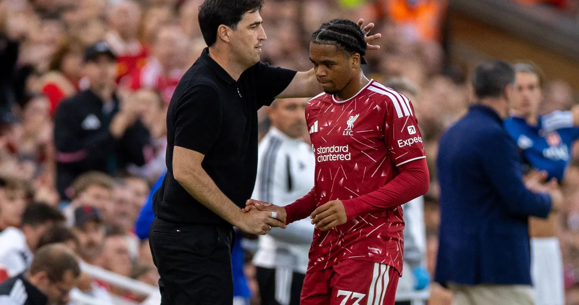 Entrenador conversando con jugador de Liverpool en el banquillo