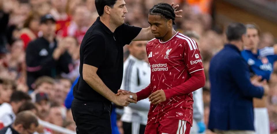 Entrenador conversando con jugador de Liverpool en el banquillo