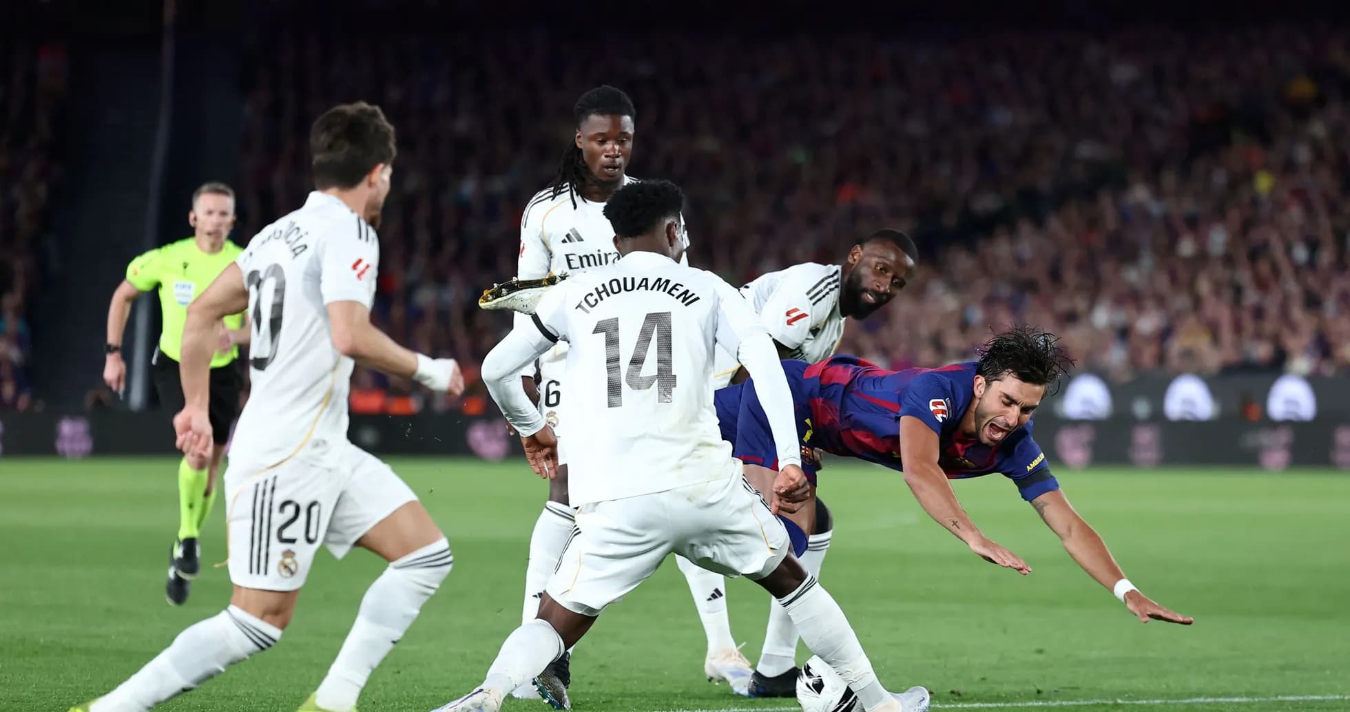 Jugador de Barcelona cayendo rodeado de defensores del Real Madrid