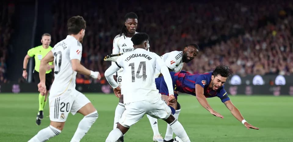 Jugador de Barcelona cayendo rodeado de defensores del Real Madrid