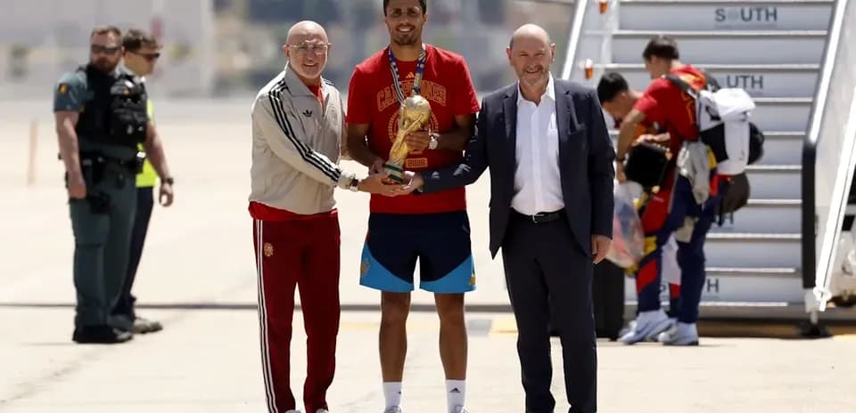 Jugador recibiendo trofeo en aeropuerto con directivos