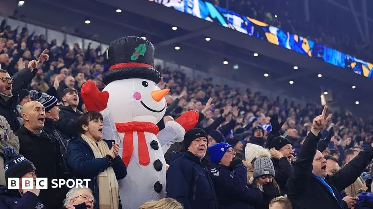 A crowd cheering with a large snowman mascot